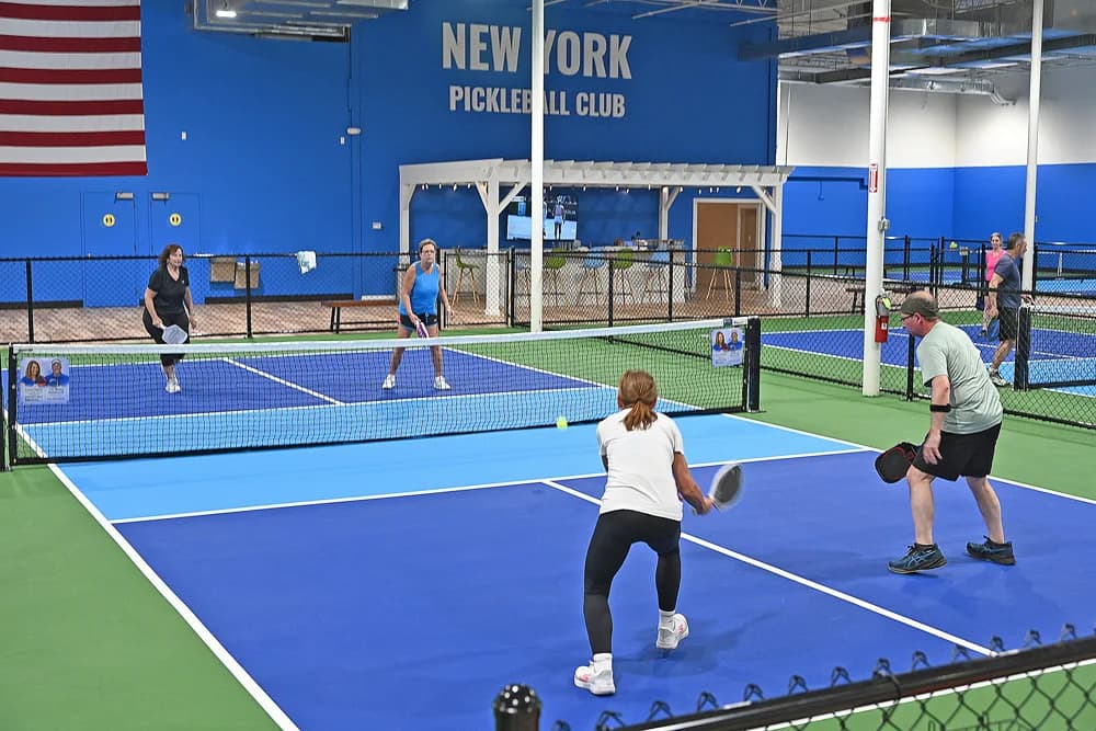 Players on the blue indoor courts at New York Pickleball Club